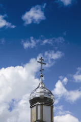 Fototapeta na wymiar Temple of Orthodox Christians with a silver cupola against a blue sky with white clouds.