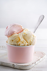 Vanilla and strawberry ice cream in a pink cup on a white background