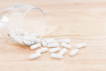 Fototapeta na wymiar White medicine capsules on wooden floor