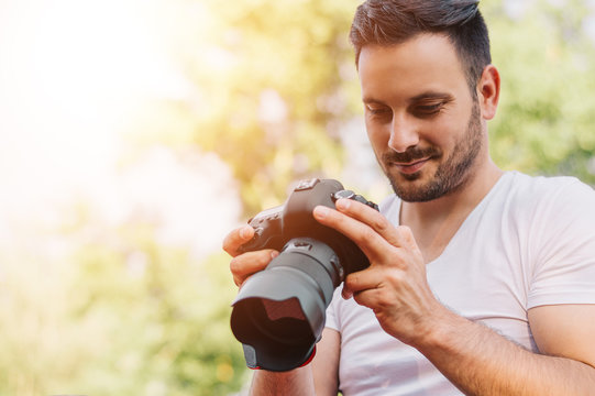 Bearded young man looking at the photos taken with DSLR