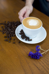 Coffee cup and coffee beans on table on a wooden desk