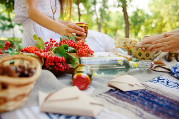 Summer picnic outdoor. Bright and colorful hipster lunch in the park. Female hands cut a piece of pie