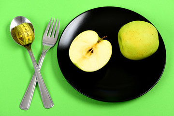 Plate in black color with whole apple fruit and half