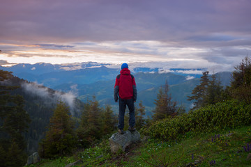 Man traveler admires a colorful sunset in the mountains