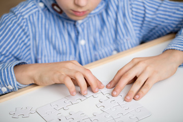 Fototapeta na wymiar Boy solving a white puzzle