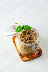 Eggplant caviar. Italian pesto of eggplant in a glass jar on a white marble table. Canning