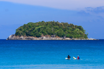 Surfers sitting on surfboard in water at the beach. Kata Beach, Phuket, Thailand.
