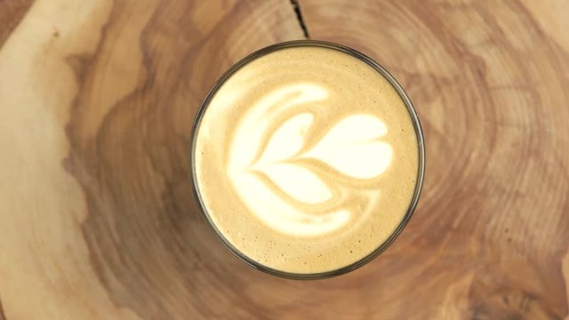 Flower latte art. Cup on wooden board spinning.