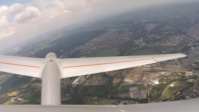 Glider flight over urban landscape. Footage from action camera placed on aircraft elevator. Soaring under clouds. 