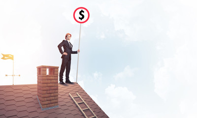 Businessman on house roof showing roadsign with money concept an