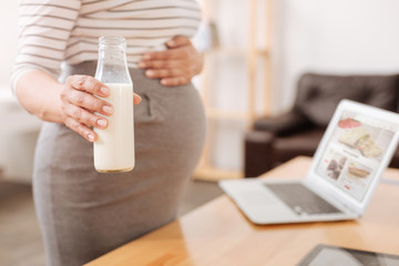 Pleasant pregnant woman holding a bottle of milk