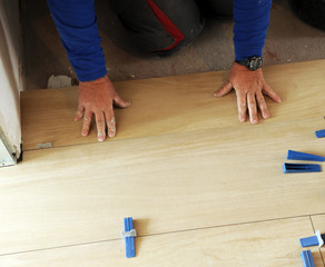 Fototapeta na wymiar Trabajador de la construcción que coloca un pavimento de gres porcelánico de imitación a madera durante la reforma de una vivienda particular