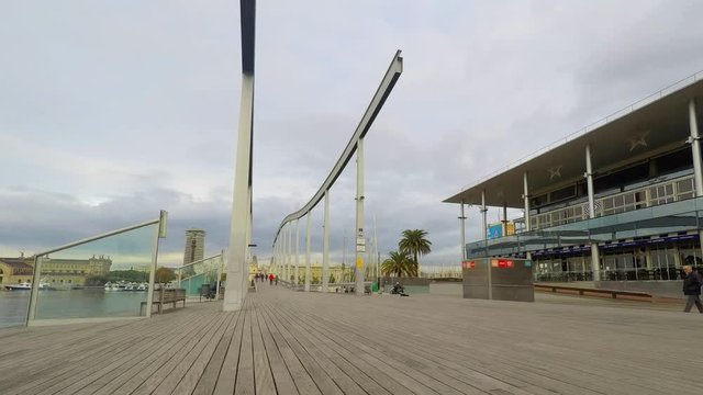 This is footage of some people crossing a closed moveable bridge in the shore area. A lot of people walk back and forth.