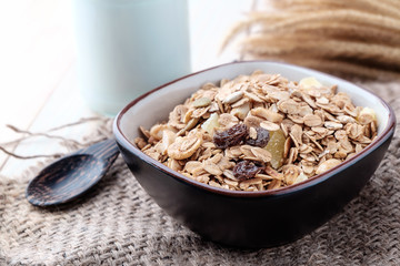 Breakfast cereals with dried fruits in a bowl on a wooden background.