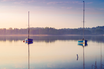 Fototapeta na wymiar Yachts float on the calm waters of the lake. Early morning. Masuria, Poland .