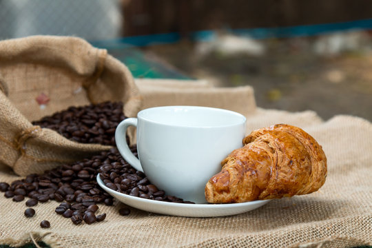 Coffee cup with Croissant and bean on the Table