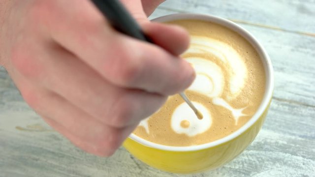 Hand of barista, latte art. Snowman picture on coffee foam.