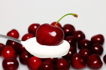 Red ripe, sweet cherry lying on a spoon in cream.