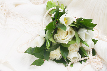 white fresh rose and tulips flowers on white chair with lace dress close up