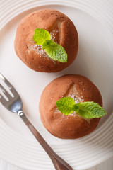 Traditional rum balls cake with mint and cocoa powder close-up on a plate. vertical top view