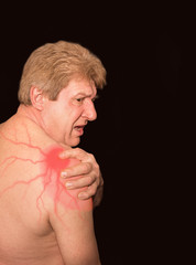 Obraz premium Close-up of senior shirtless man with shoulder pain over black background
