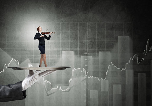 Attractive businesswoman on metal tray playing violin and graphs at background