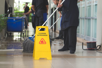 Cropped image of woman in protective gloves using a flat wet-mop and machine while cleaning floor