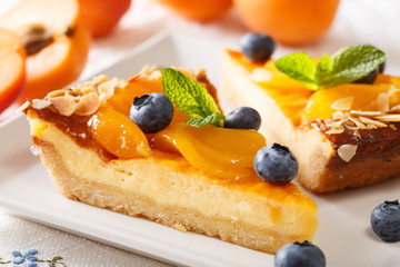 Delicious cheesecake with apricots, blueberries and almonds close-up on a plate. horizontal