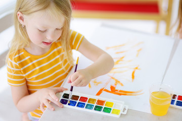 Cute little girl drawing with colorful paints at a daycare. Creative kid painting at school.
