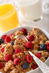 Delicious breakfast of granola with dried raspberries, nuts and blueberries, milk and juice macro.