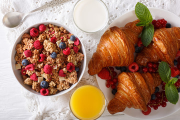 Healthy breakfast: granola with berries and croissants, milk and juice close-up. horizontal top view