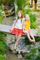 Naklejka premium Two adorable little sisters laughing and hugging on summer day in a park