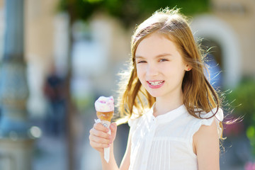 Adorable little girl eating tasty fresh ice cream outdoors on warm summer day