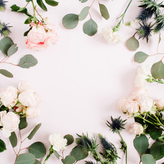 Round frame wreath made of beige rose flowers, eringium flower, eucalyptus branches and leaves on pale pastel pink background. Flat lay, top view. Floral background