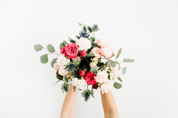 Girl's hands holding beautiful flowers bouquet: bombastic roses, blue eringium, eucalyptus, isolated on white background. Flat lay, top view. Floral composition