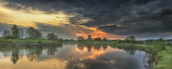 Panoramic landscape of river in autumn morning at sunrise with colorful sky and gray clouds