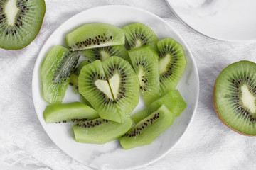 Top view of pieces of fresh kiwi in the shape of a heart on a white plate. Healthy eating concept. Flat lay.