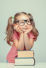smiling beautiful cute little girl leaning on thick books
