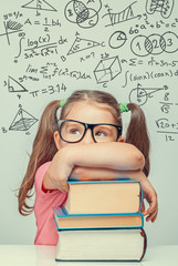 beautiful cute little genius girl with books. Math formulas, problems over her head