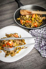 Plate with chicken meat and vegetable on wooden table.