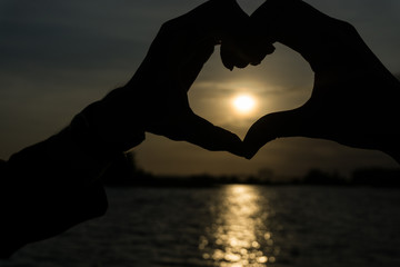 Hand shaped heart in sunrise