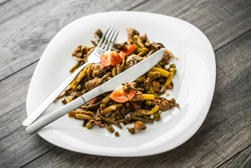 Plate with chicken meat and vegetable on wooden table.