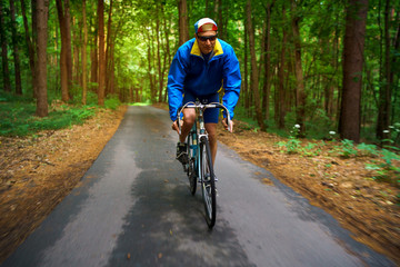 Obraz premium Middle-aged man is riding a road bike along a forest road