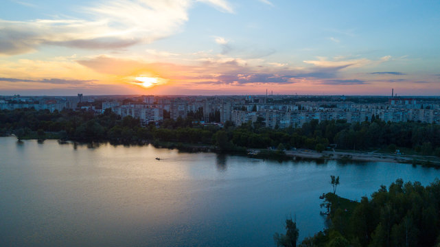 Flying over the trees and lake in the city at dawn - aerial photo