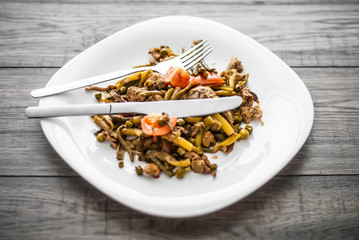 Plate with chicken meat and vegetable on wooden table.