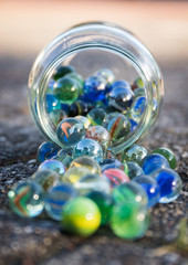 Glass jar full of crushers, fallen on the street. Front view of jar.
Bright picture, with blue as main color.
Front and background blurred.
Other colors red, green, yellow.