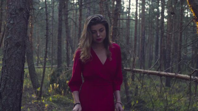 Young woman in red dress walking in the forest