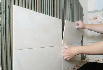 Tilers hands are  installing a ceramic tile.