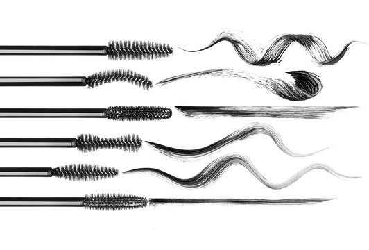 Set of various mascara brushes with mascara strokes on white background