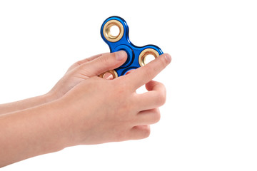 Hands of child prepared to twist a blue shiny spinner, isolated on a white background